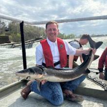 Newly appointed Director of the Missouri Department of Conservation, Jason Sumners, holding a sturgeon on a boat deck